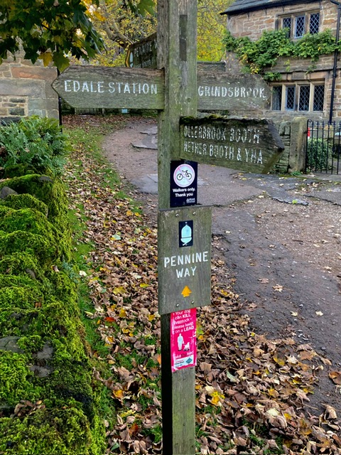 Signpost showing directions to Edale Station, Grindsbrook, and the start of the Pennine Way.