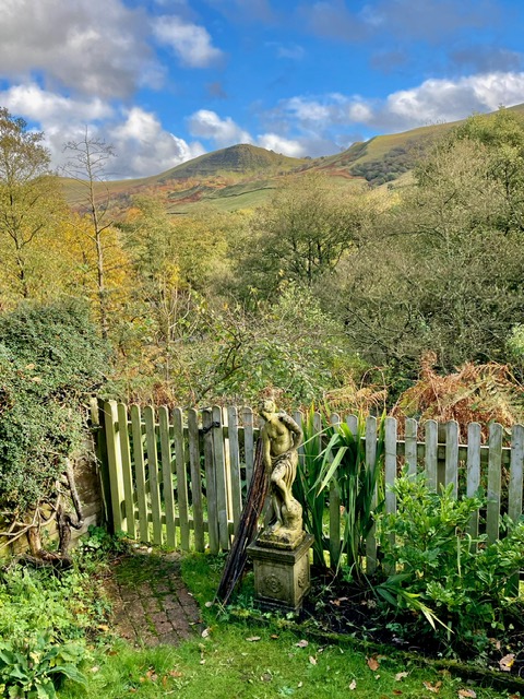 View from the private back garden, with a charming statue and scenic hills in the distance.